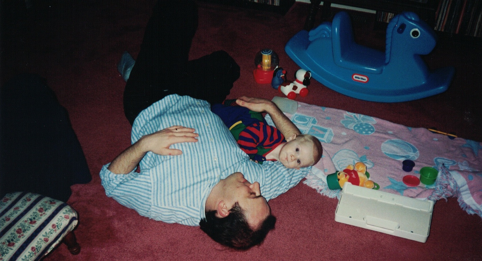 Family photo of my dad laying on the floor with me when I was a baby